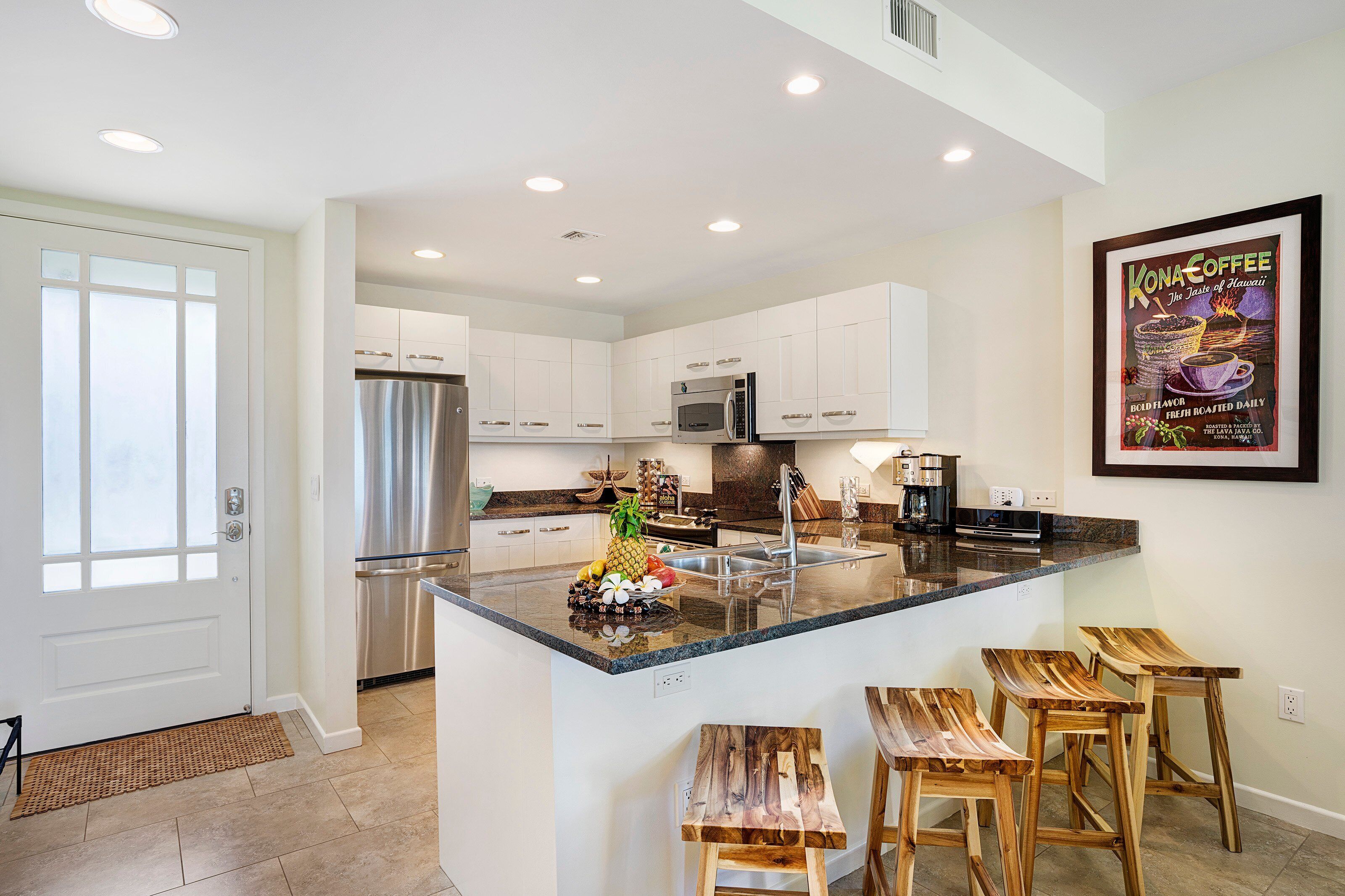 A modern kitchen with white cabinets, stainless steel appliances, and a central island with bar stools.