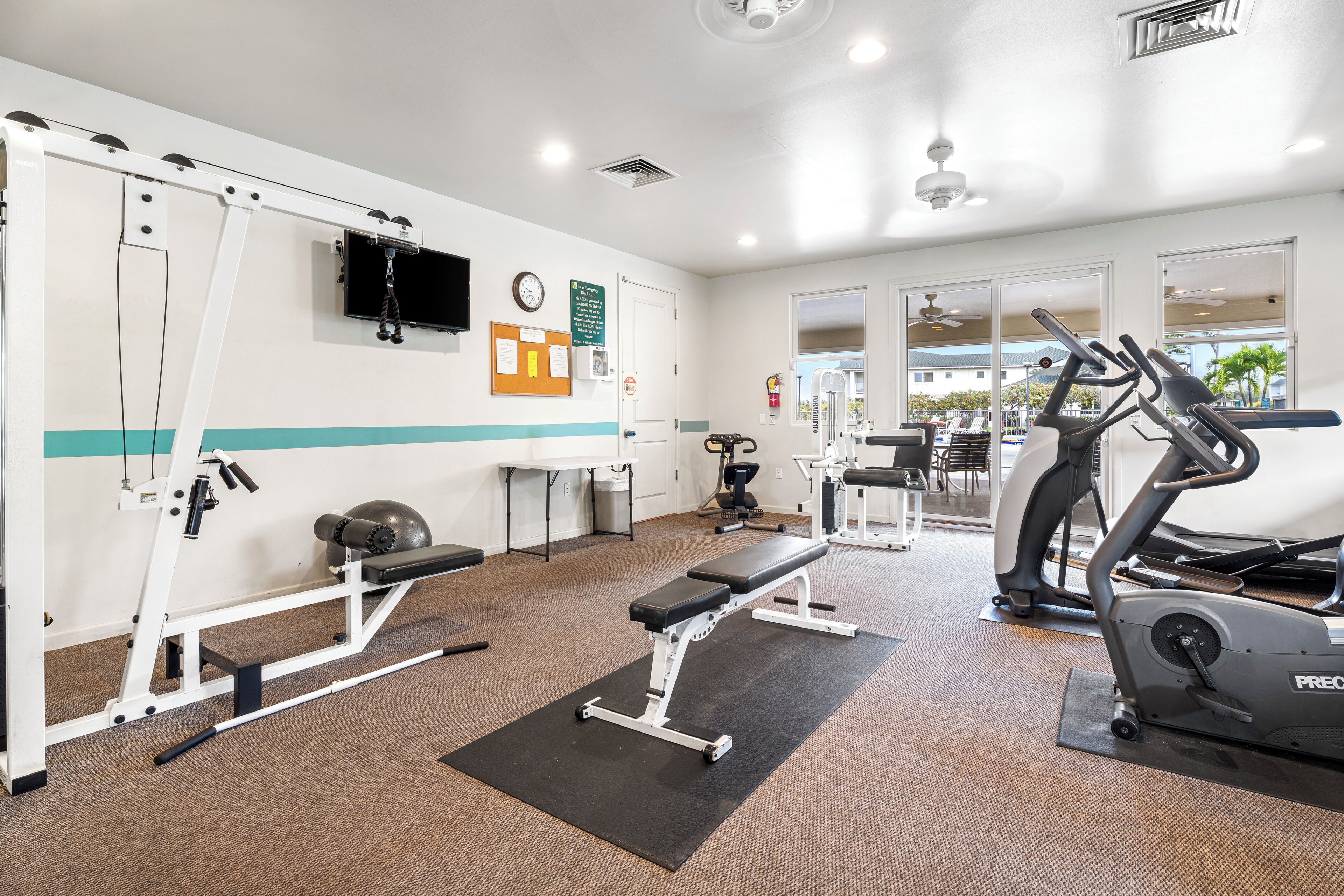 Une salle de sport équipée de matériel d’exercice, d’un banc et d’un tapis de course.
