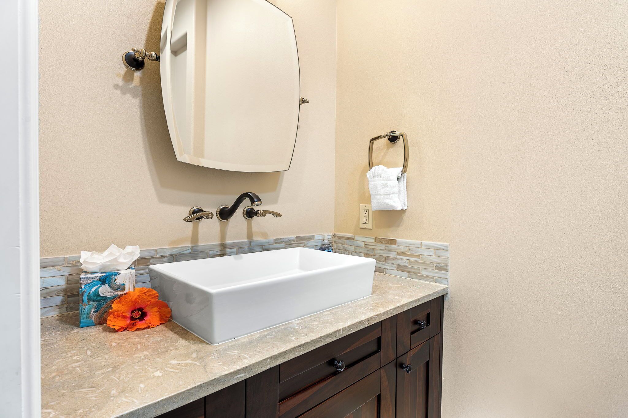 Une salle de bain avec un lavabo blanc, un porte-serviettes et un boîte à mouchoirs.