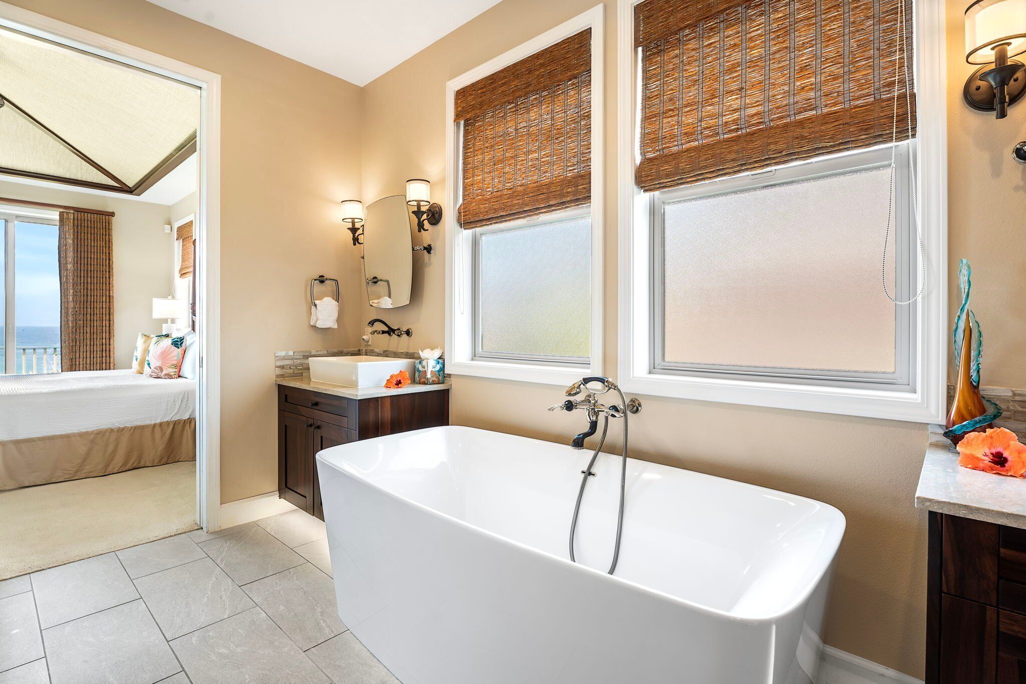 A modern bathroom with a freestanding bathtub, a vanity with a mirror, and a window with a view.