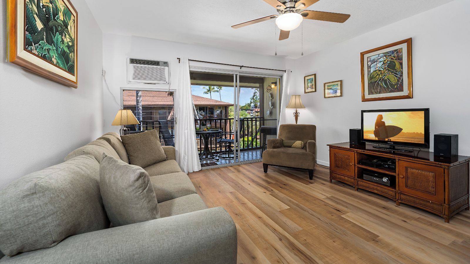 A living room with a sofa, armchair, TV, and wooden flooring.
