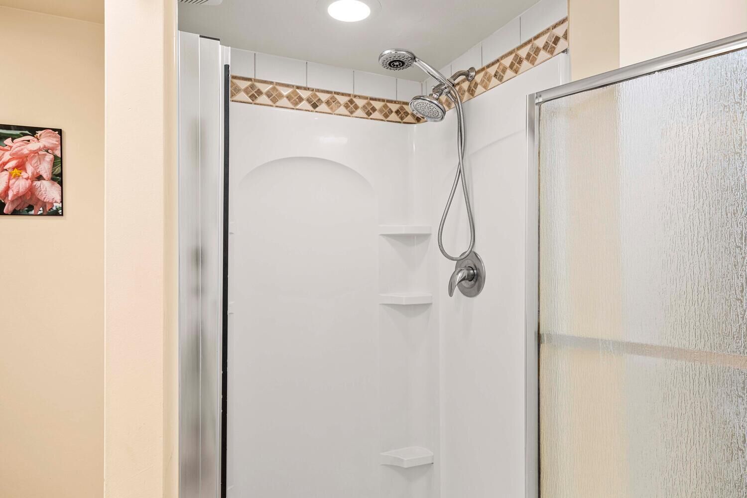 A shower with a handheld showerhead and a wall-mounted faucet.