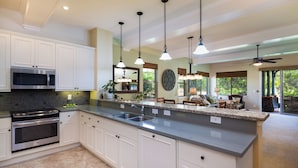 A modern kitchen with white cabinets, a stainless steel microwave, and a granite countertop. - Concierge Included - AC - Wifi - Mauna Lani Beach Access - Vrkcv (Kamuela)
