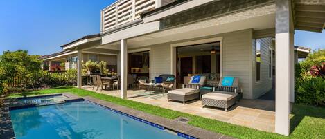 A modern house with a swimming pool, outdoor seating, and a covered patio area.