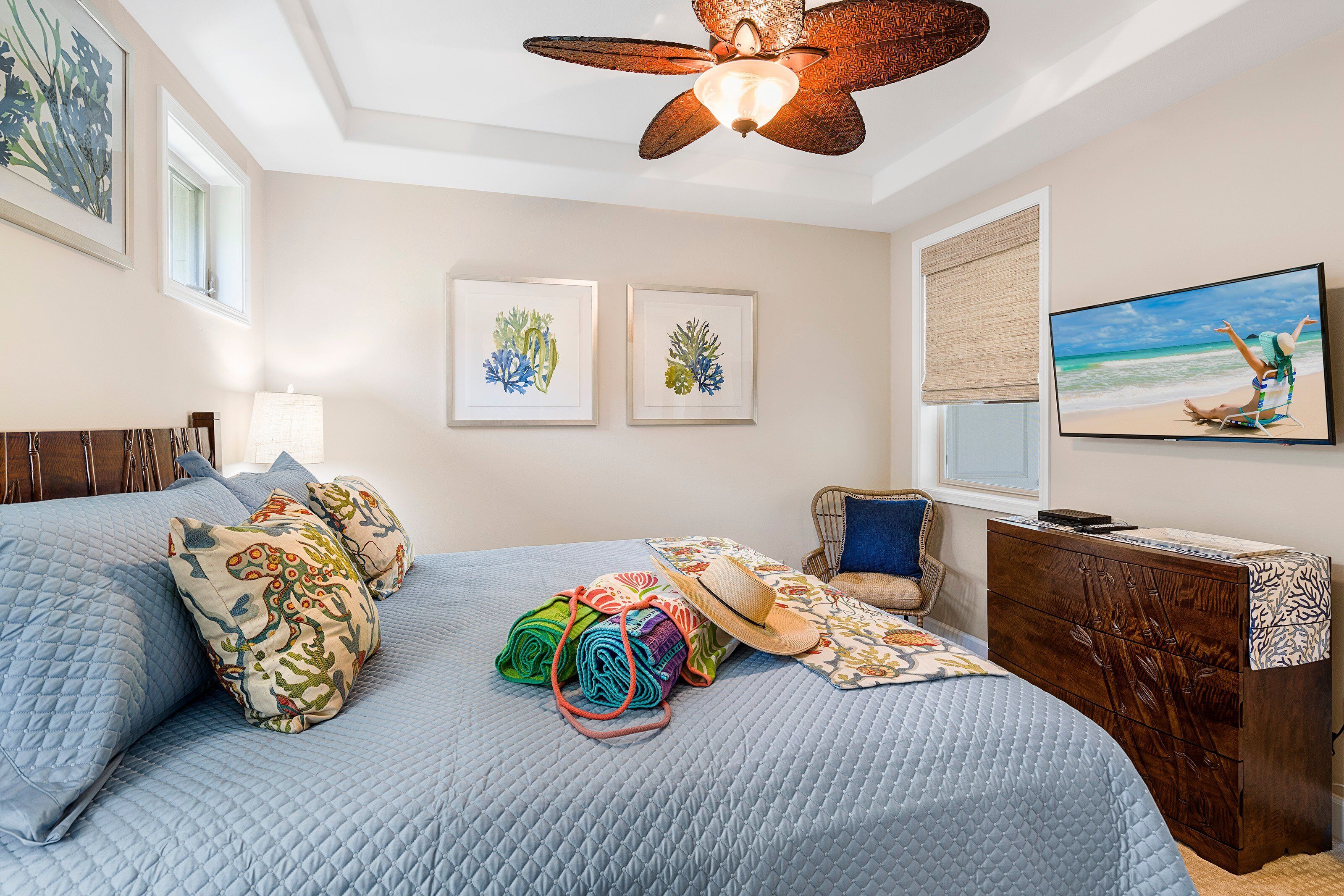 A bedroom with a bed, a dresser, a chair, a television, and artwork on the wall.