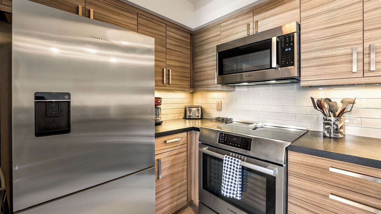 Une cuisine moderne dotée d’appareils électroménagers en acier inoxydable, de meubles en bois et d’un four à micro-ondes.