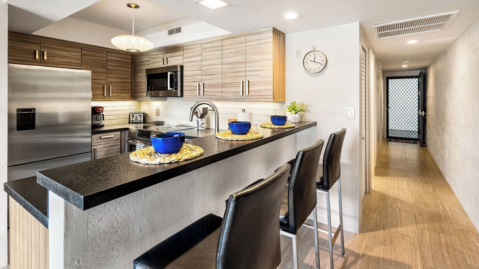 A modern kitchen with a central island, stainless steel appliances, and wooden cabinetry.