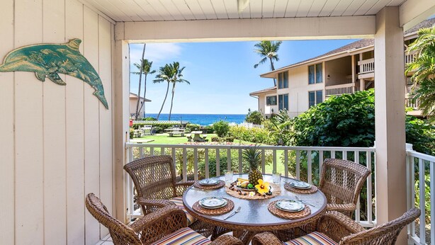 A round table with wicker chairs and a view of the ocean.