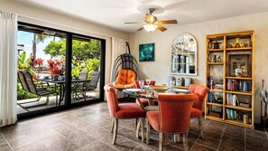 A dining area with a glass door leading to a patio, a ceiling fan, and a bookshelf filled with books and decorative items.
