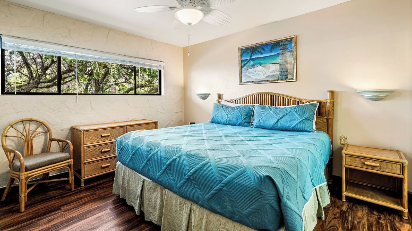 A bedroom with a large bed, a chair, a nightstand, and a window with a view of trees.