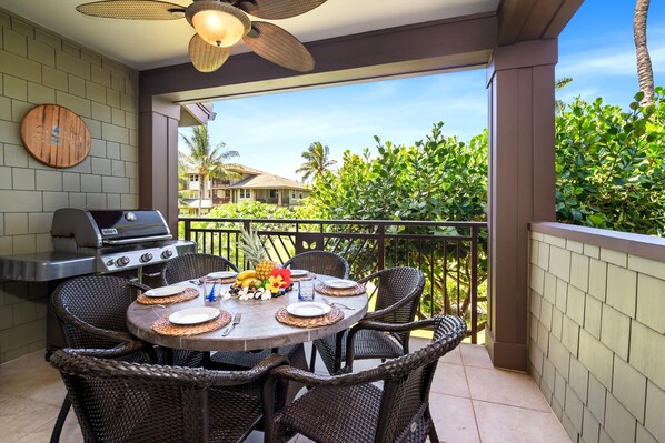 A covered outdoor dining area with wicker chairs, a round table, and a grill.