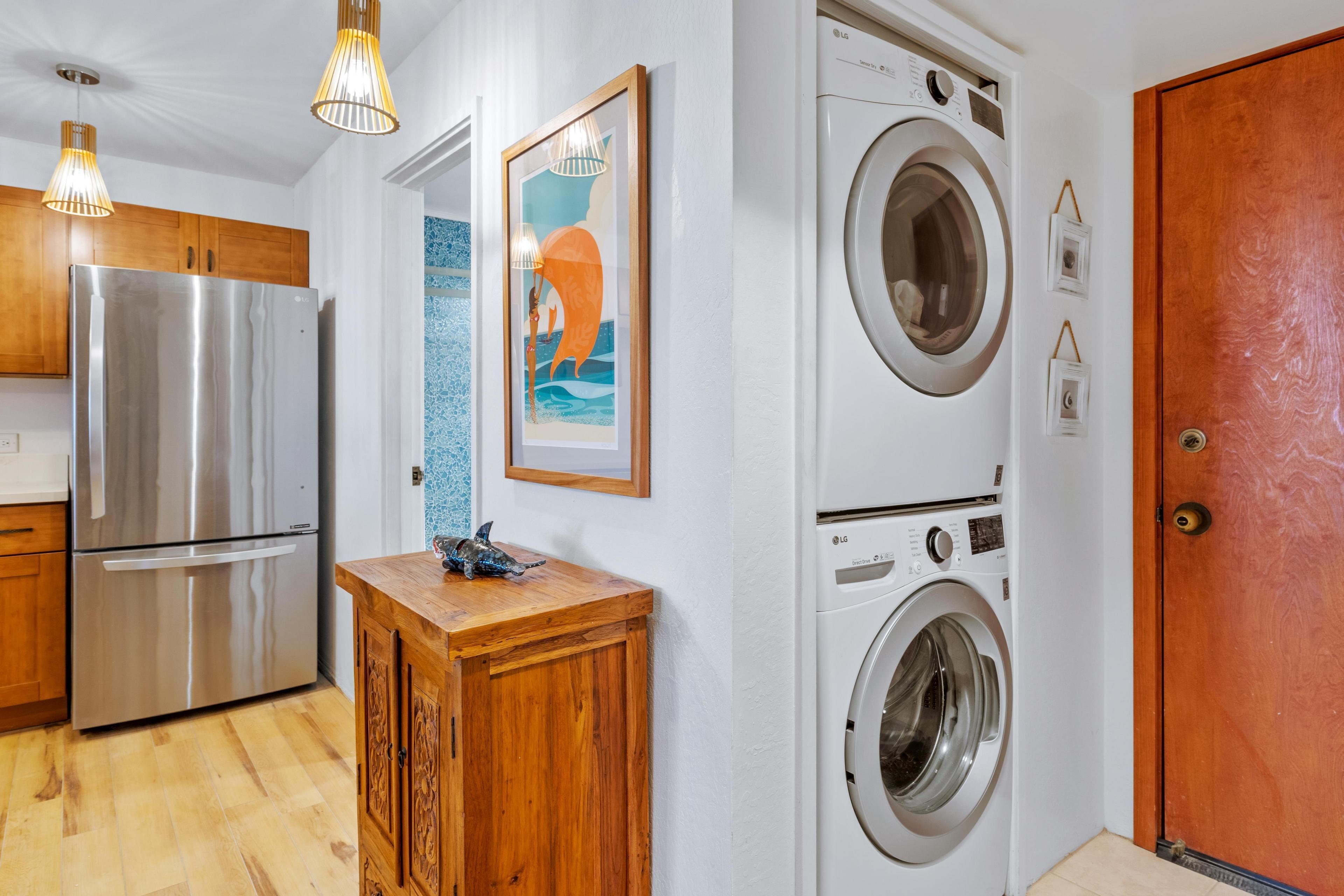 Una cocina con un refrigerador de acero inoxidable, gabinetes de madera y una lavadora.