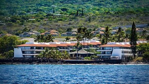 A coastal hotel with multiple buildings, a rocky shoreline, and lush greenery in the background. - Oceanfront Complex - No Stairs - AC - Wifi - Vrkcv (Kailua-Kona)