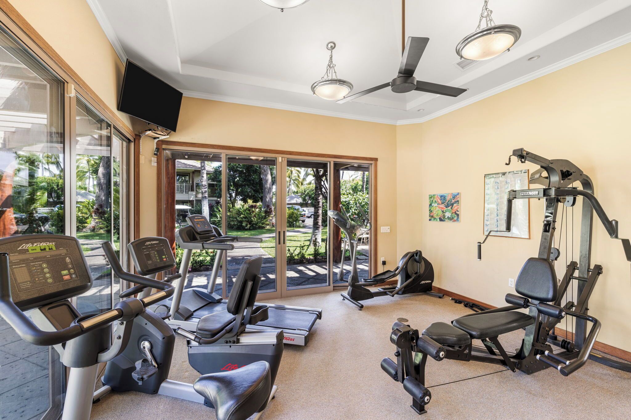 Een fitnessruimte met loopbanden, elliptische trainers en gewichten.