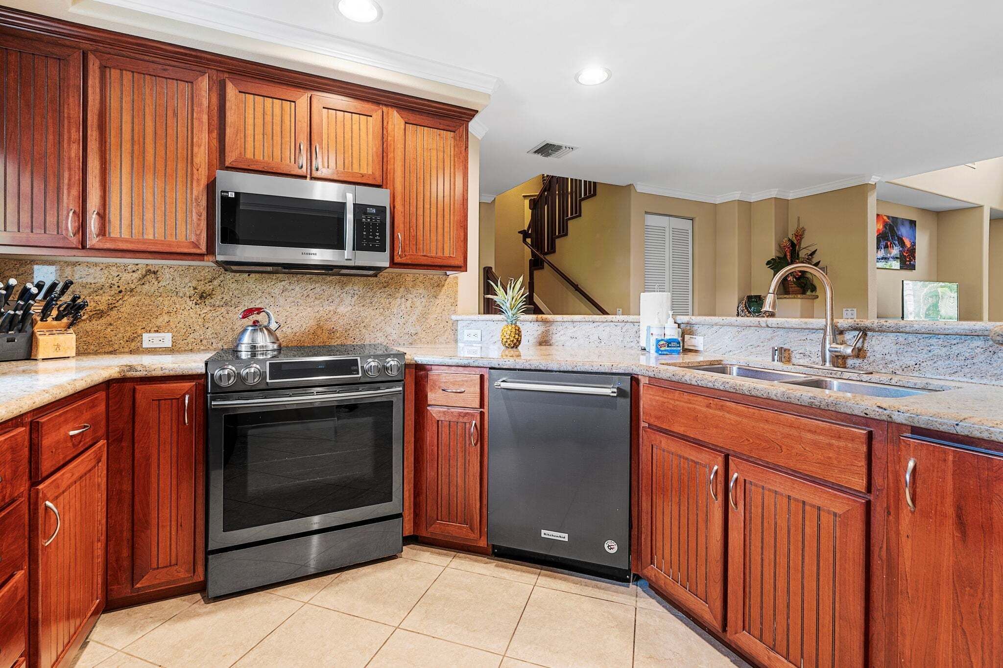 A kitchen with wooden cabinets, stainless steel appliances, granite countertops, and a built-in dishwasher.