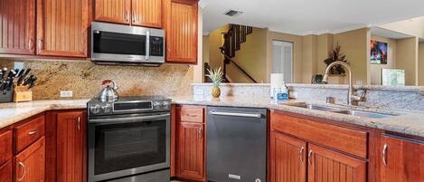 A kitchen with wooden cabinets, stainless steel appliances, granite countertops, and a built-in dishwasher.