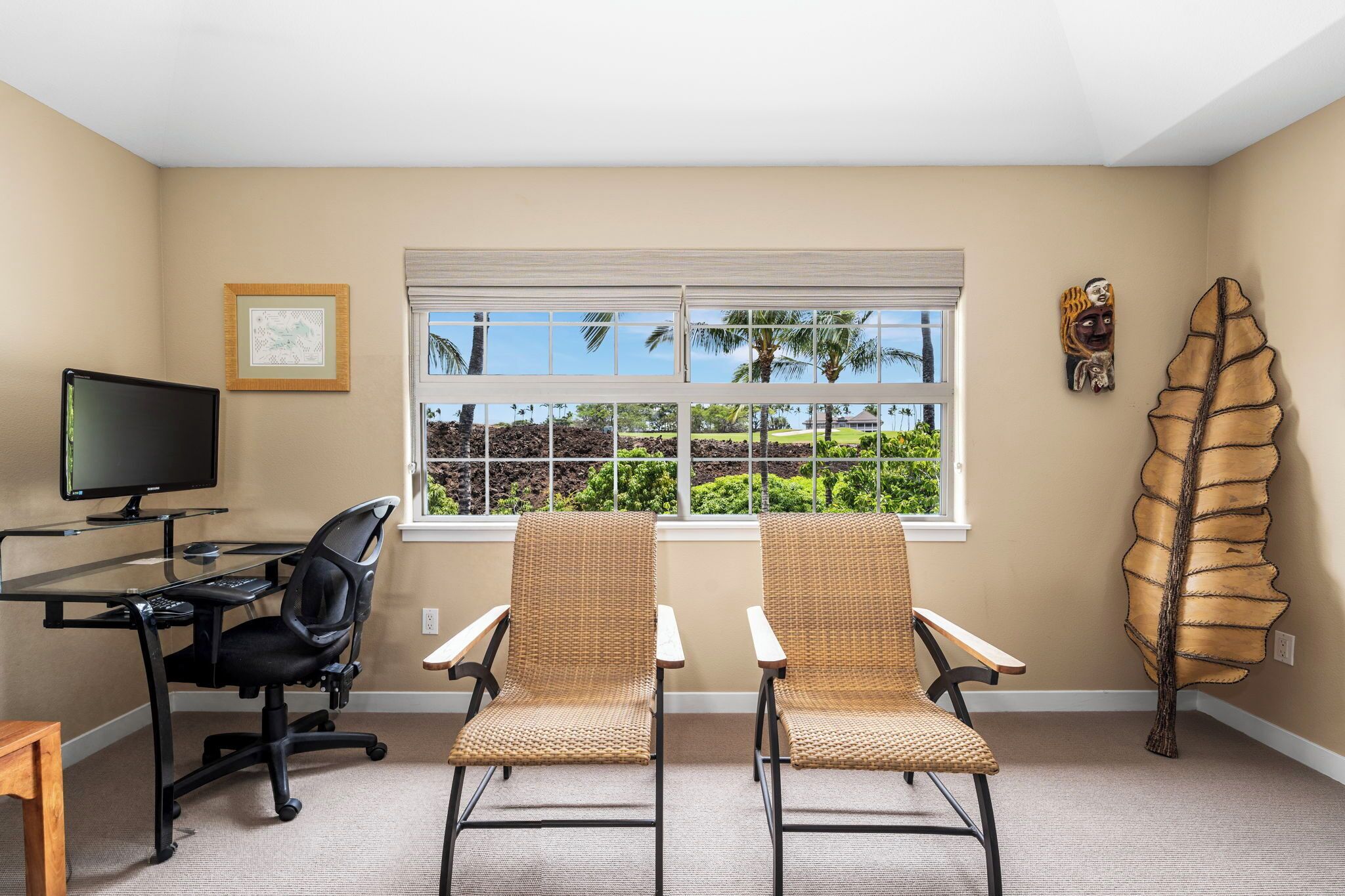 A room with a desk, two chairs, a computer, a window with blinds, and a wall decoration.