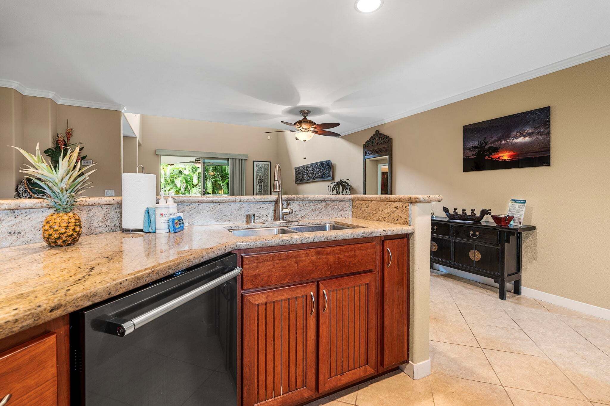 A kitchen with granite countertops, wooden cabinets, a dishwasher, and a ceiling fan.