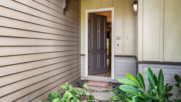 Une entrée de maison avec une porte sombre, une boîte aux lettres et un petit jardin agrémenté de plantes.