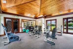 A gym with exercise equipment, a stone wall, and a view of the outdoors. - Peaceful Mauna Lani Getaway - Pool, Golf & Private Beach Access - Vrkcv (Kamuela)