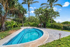 A swimming pool with a stone deck, surrounded by lush greenery and palm trees. - Peaceful Mauna Lani Getaway - Pool, Golf & Private Beach Access - Vrkcv (Kamuela)