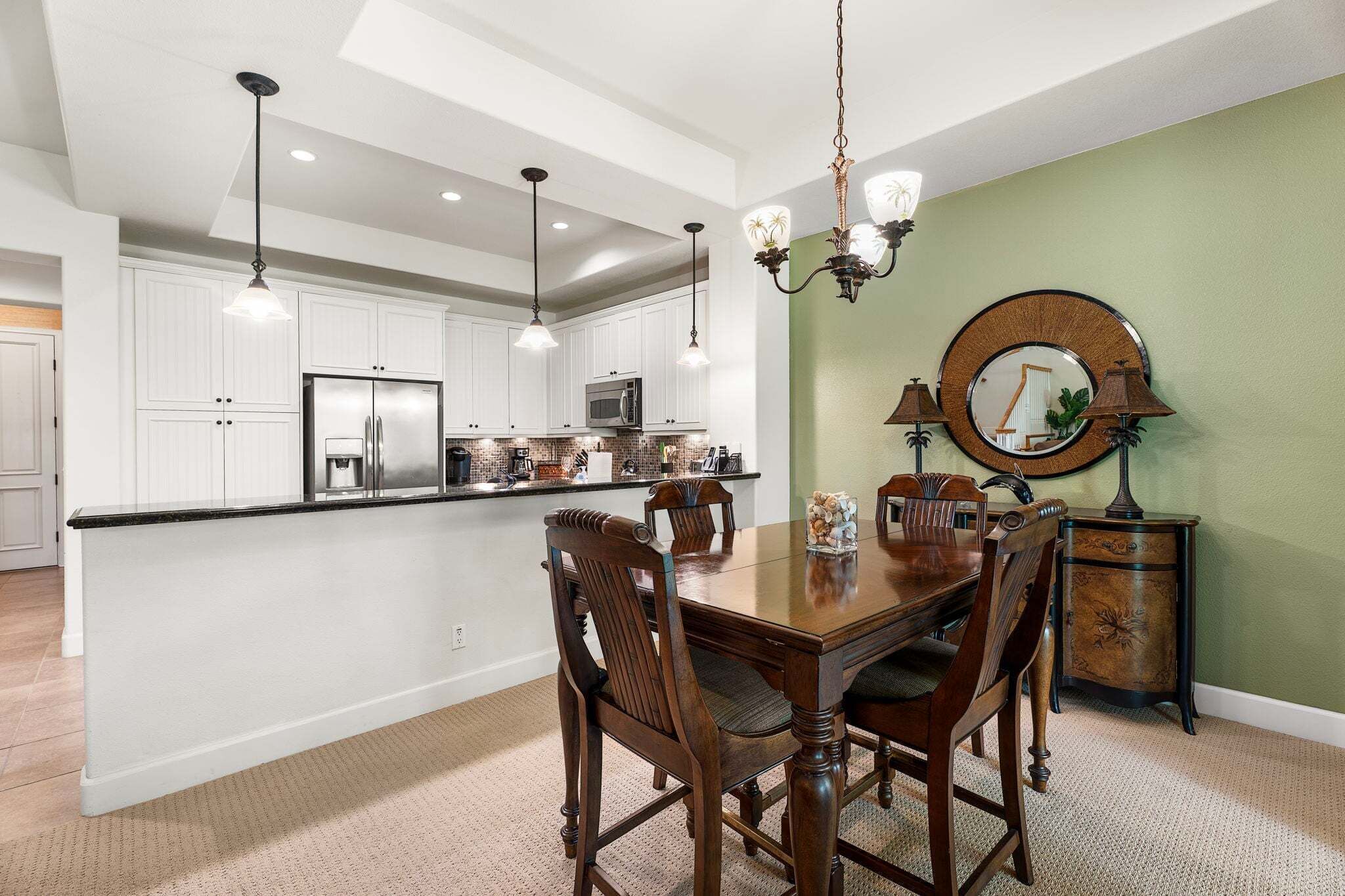A modern kitchen with white cabinetry, a central island, and a dining area with a wooden table and chairs.