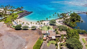Un resort costero con playa, palmeras y vista despejada al océano.
