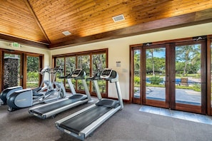 A gym with treadmills, elliptical machines, and a stone wall.