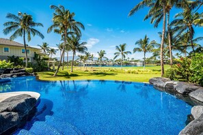 A swimming pool with clear blue water, surrounded by palm trees and a well-maintained lawn. - Top Floor - Amazing Golf & Mountain Views - Walk to Restaurants - Vrkcv (Waikoloa)