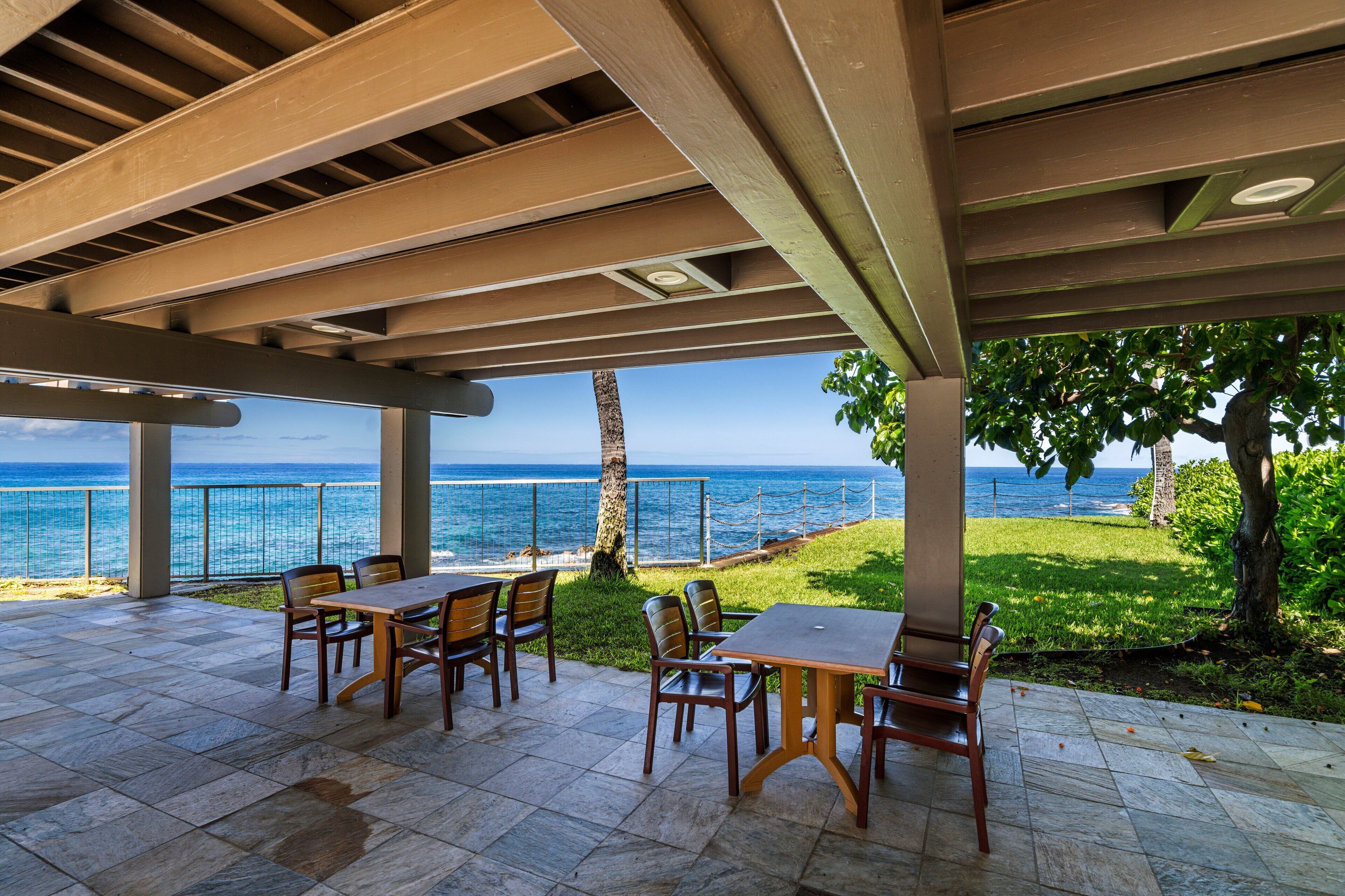 An outdoor patio with tables and chairs, overlooking a body of water.