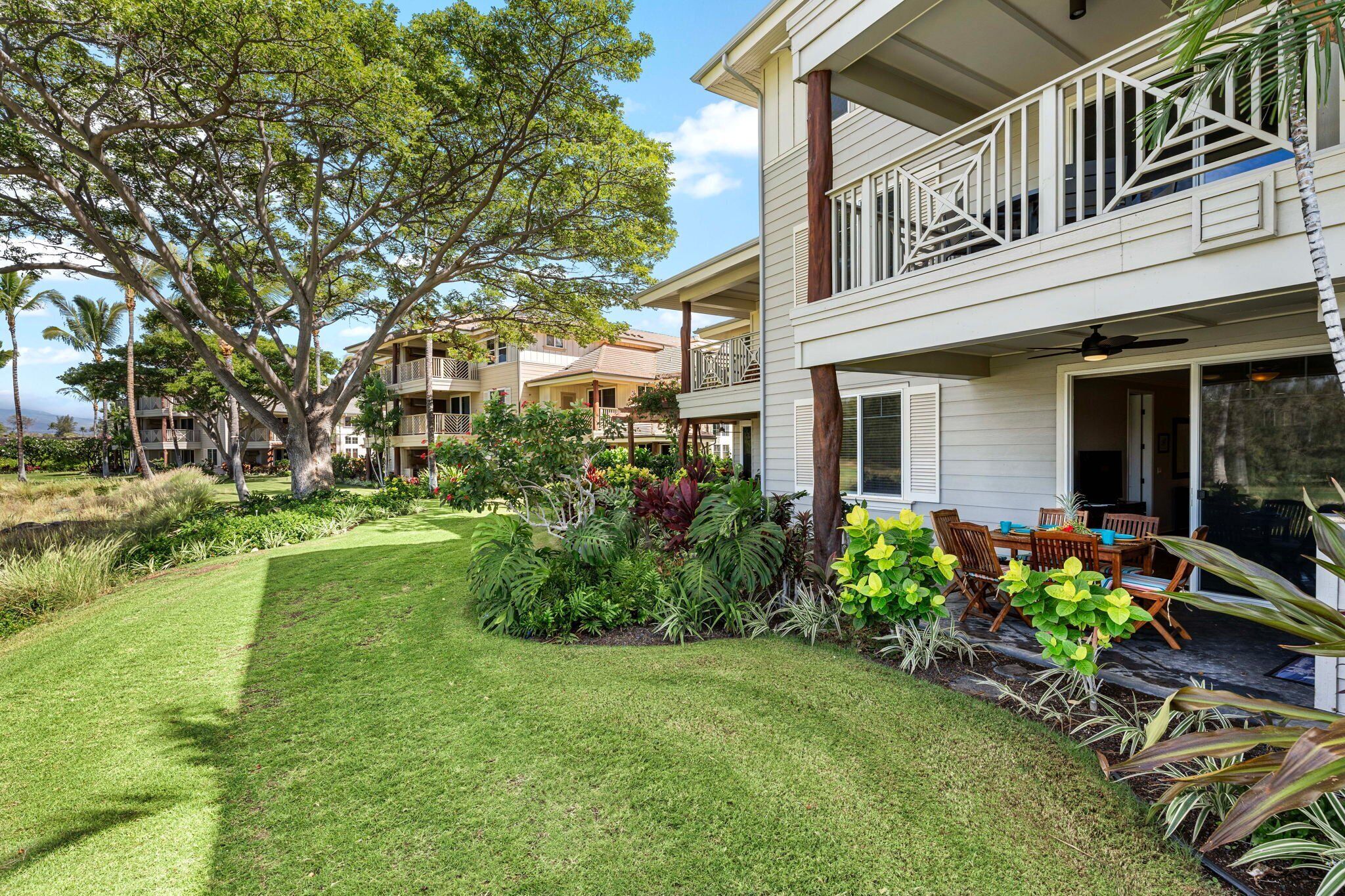 A two-story building with a balcony, surrounded by lush greenery and a well-maintained lawn.