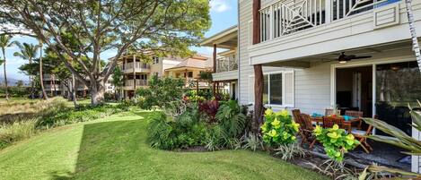 A two-story building with a balcony, surrounded by lush greenery and a well-maintained lawn.