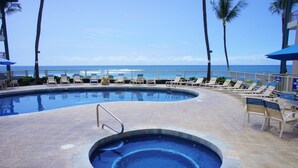 A pool area with lounge chairs and a view of the ocean. - Ocean Front - Walk to Kona Town! - Vrkcv (Kailua-Kona)