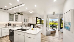 Cozinha moderna com armários brancos, uma ilha central e vista para o espaço da varanda externa.