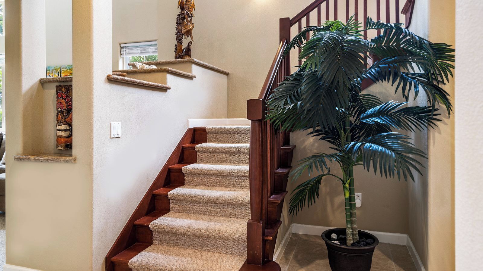 Una escalera alfombrada con barandillas de madera y una planta en maceta.