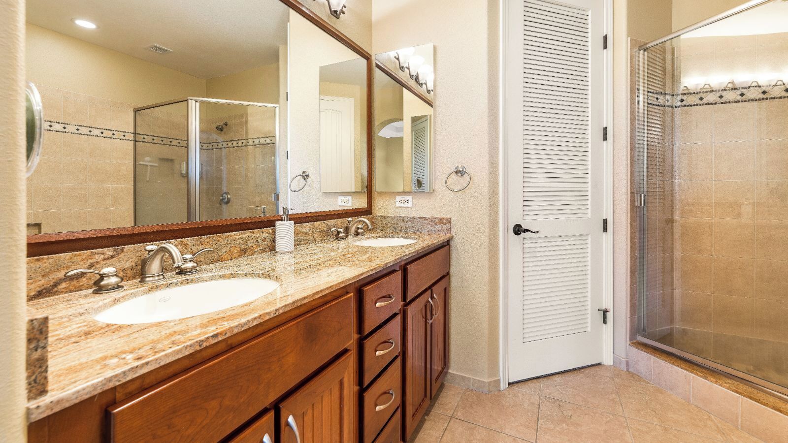 A bathroom with two sinks, a large mirror, and a shower area.