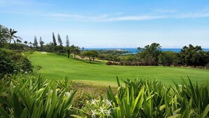A golf course with a clear view of the ocean and a distant building. - Fantastic Ocean & Golf Course Views - Close to Shopping & Beaches - Vrkcv (Kailua-Kona)