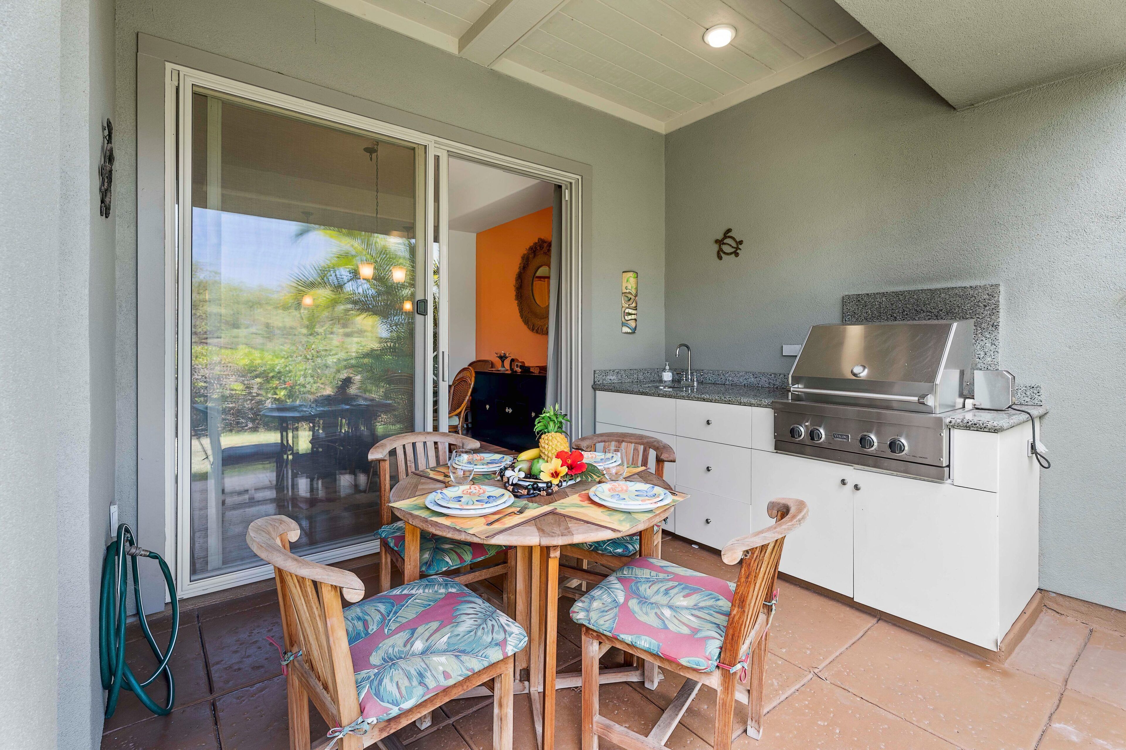 An outdoor kitchen with a grill, dining table with chairs, and a sliding glass door leading to a patio.