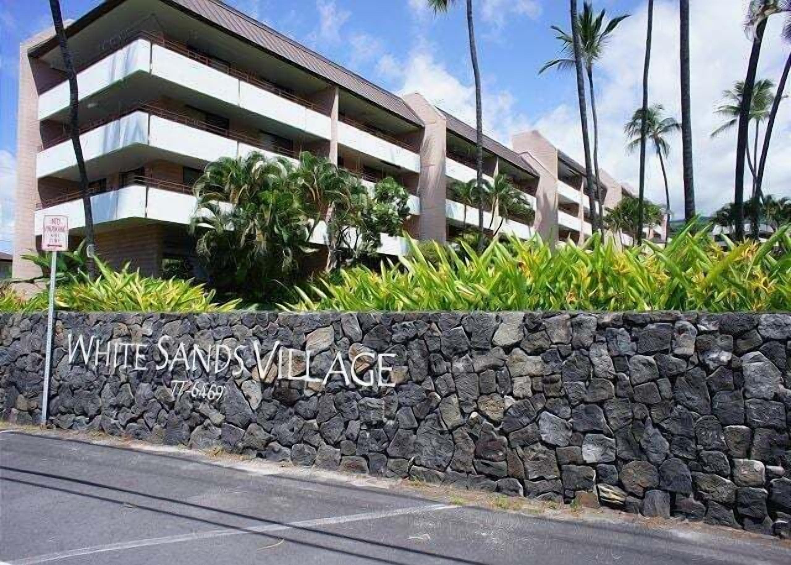 A multi-story building with a stone wall in front, labeled "WHITE SANDS VILLAGE."
