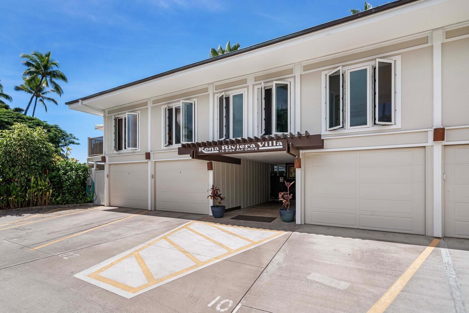 Un hôtel à la façade blanche, doté de nombreuses fenêtres et d’une enseigne indiquant « Kona Riviera Villa ».