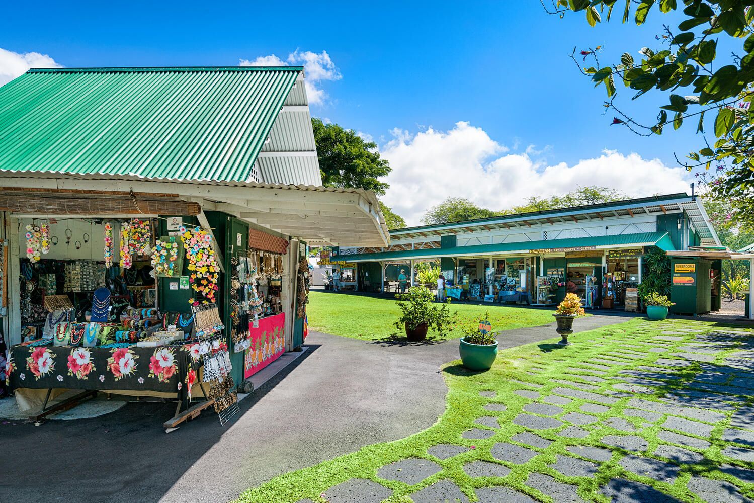 Ein Marktplatz mit Ständen, die Schmuck und Kunsthandwerk anbieten, einem überdachten Gang und einem Gebäude mit Gründach.