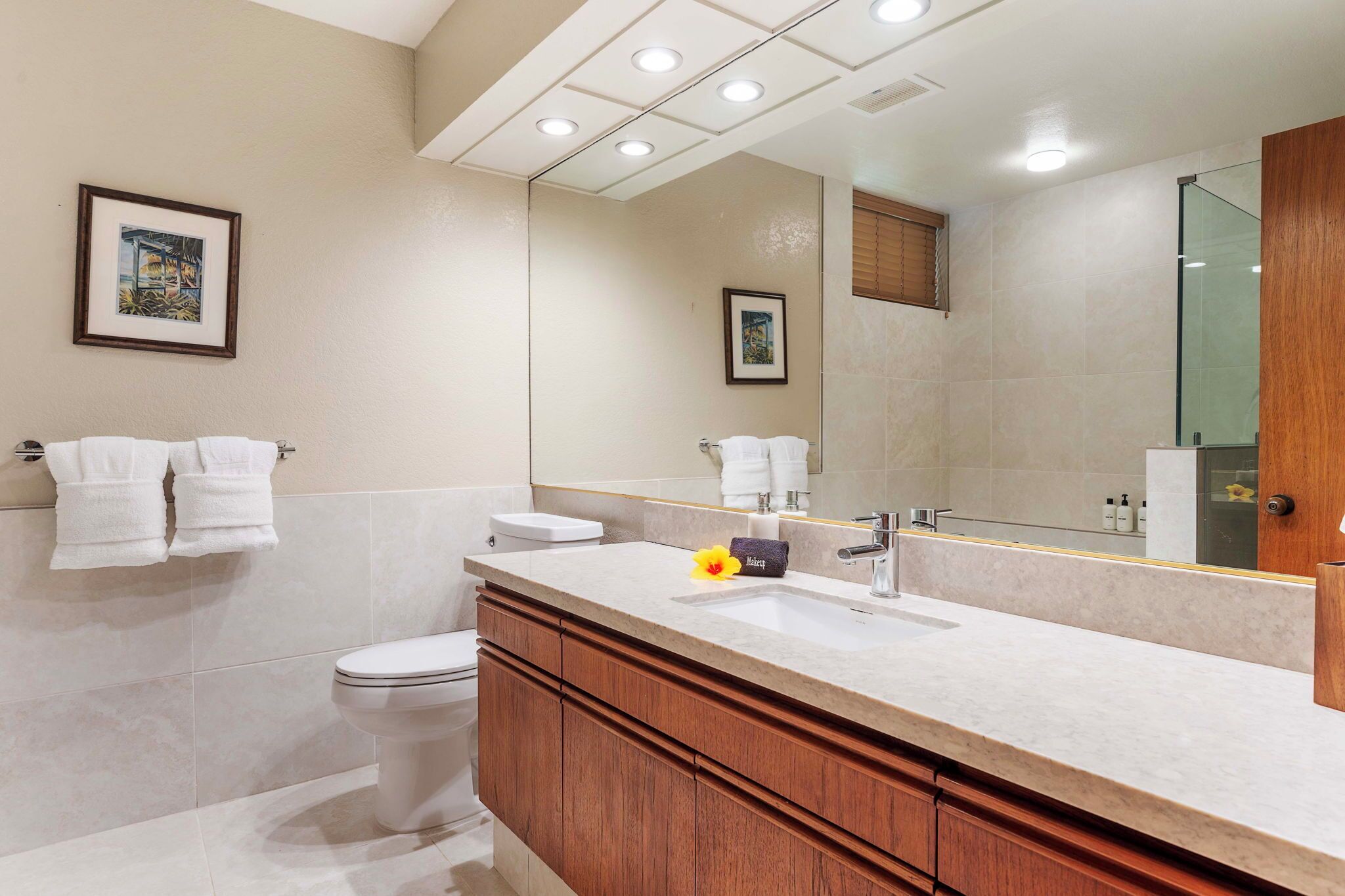 A modern bathroom with a large mirror, a sink, and a toilet.
