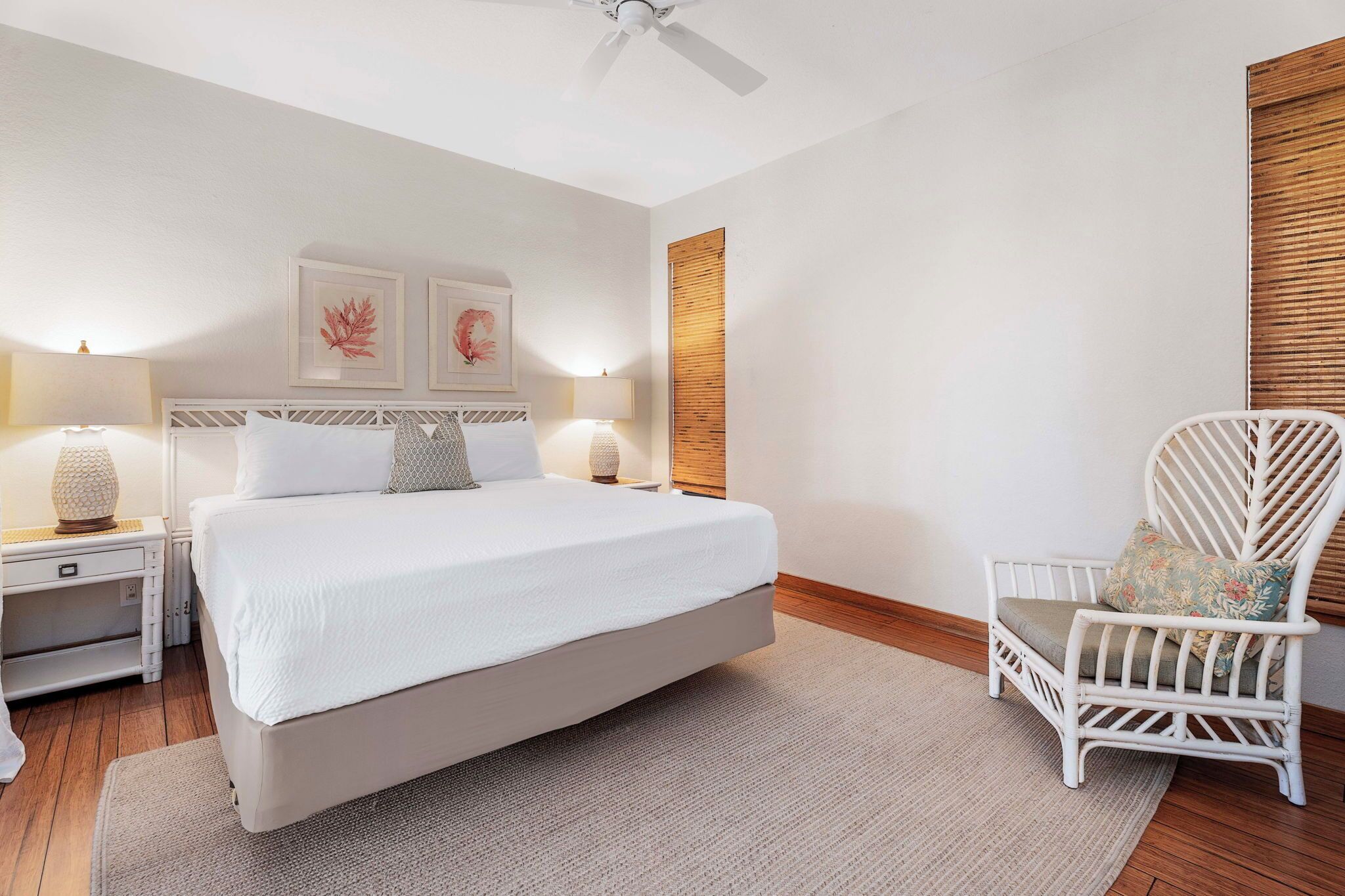 A neatly arranged bedroom with a large bed, bedside lamps, a chair, and framed artwork on the wall.