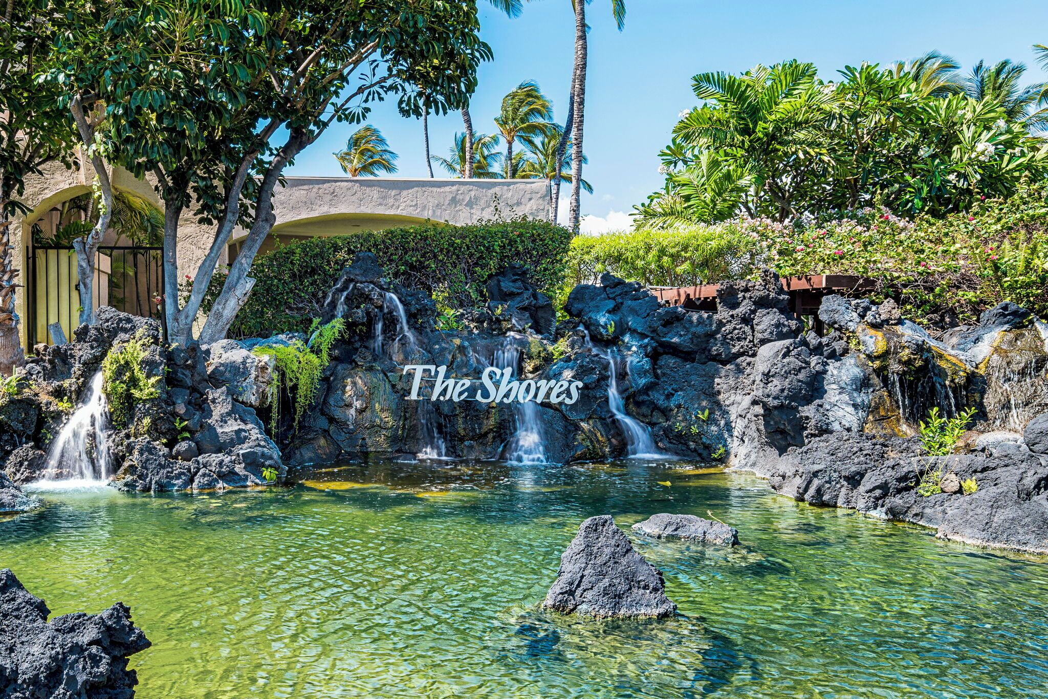 Un resort tropical con piscina cristalina, cascadas y exuberante vegetación.