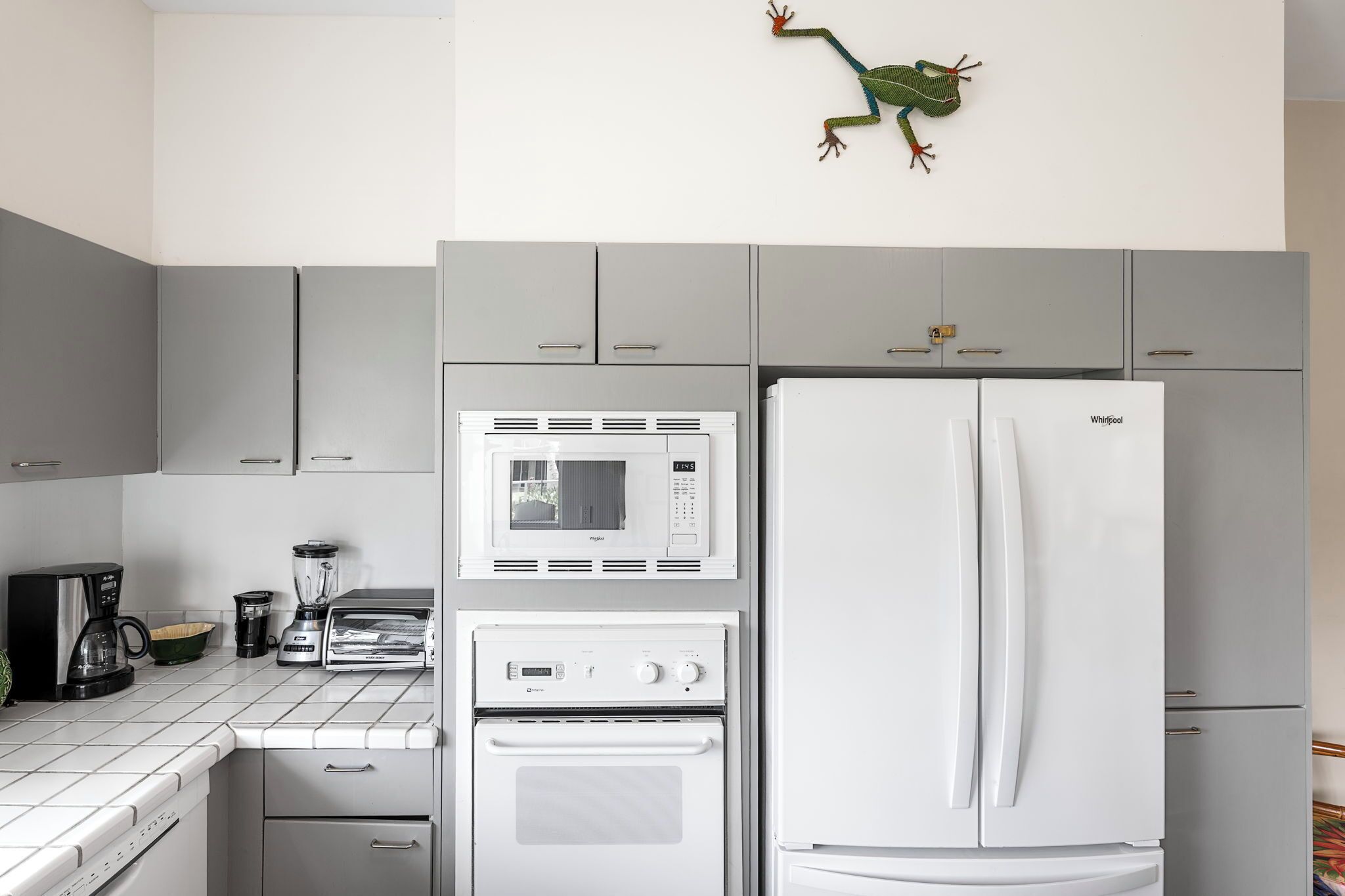 Una cocina con un refrigerador blanco, microondas y horno, además de una licuadora y una cafetera.
