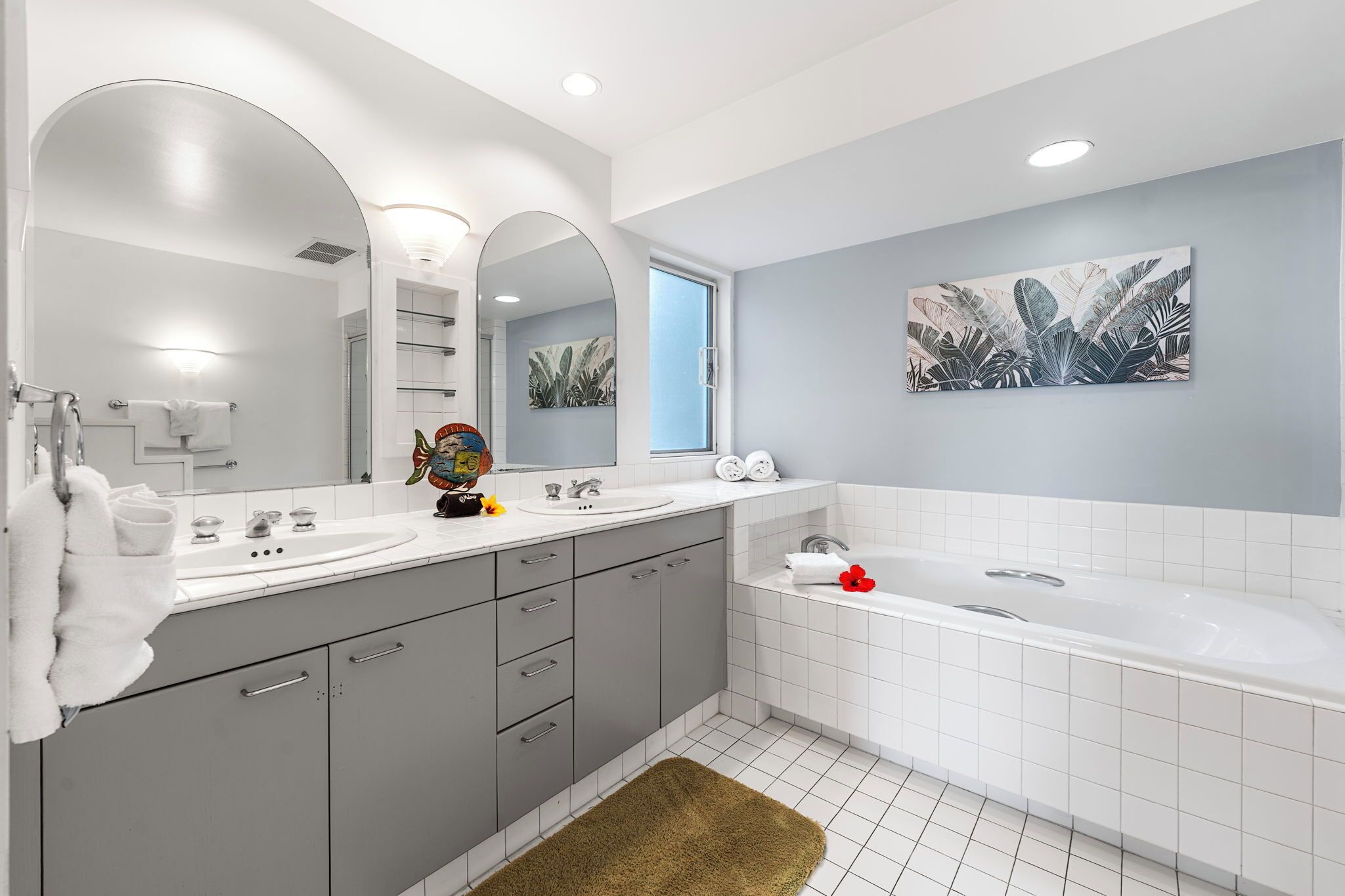 A modern bathroom with a large mirror, a bathtub, and a sink.