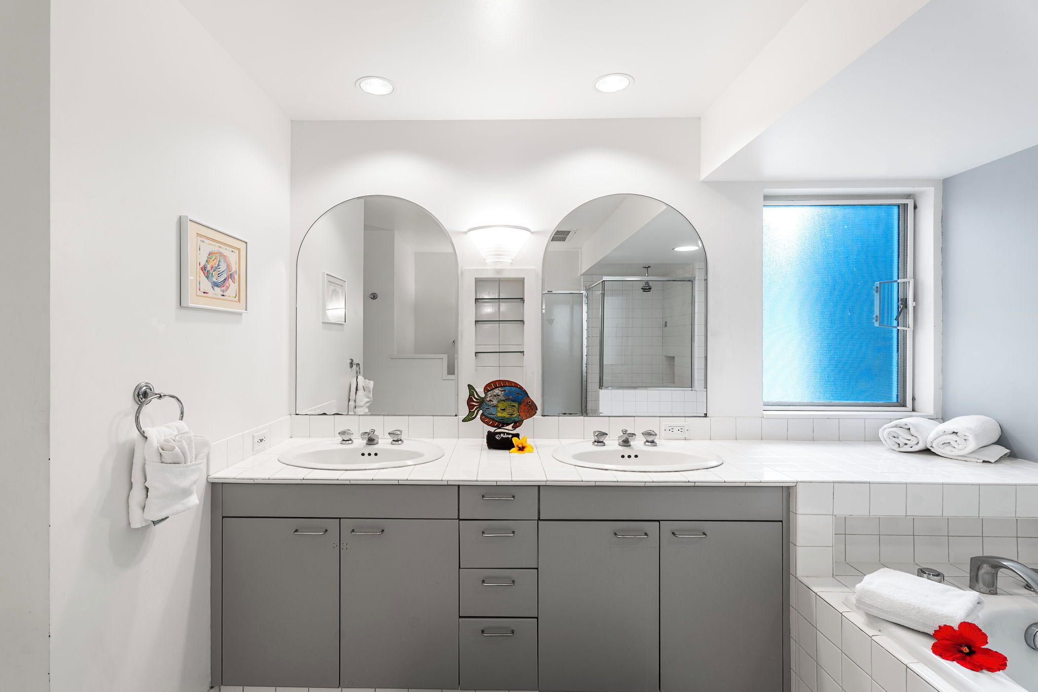 A modern bathroom with two sinks, a large mirror, and a window.