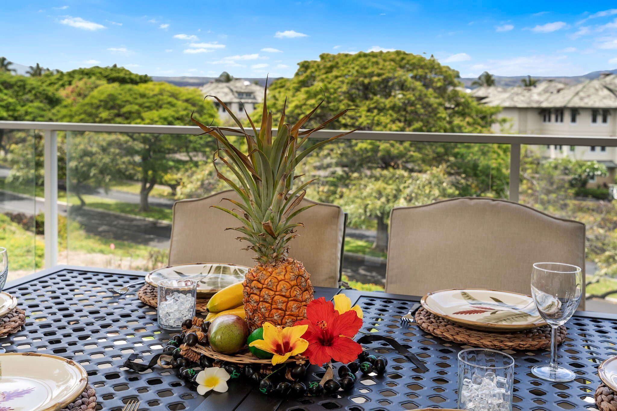 A dining table set with plates, cutlery, a pineapple, and tropical flowers.