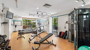 Une salle de sport équipée de divers appareils d’exercice, d’un téléviseur et offrant une vue sur l’extérieur.