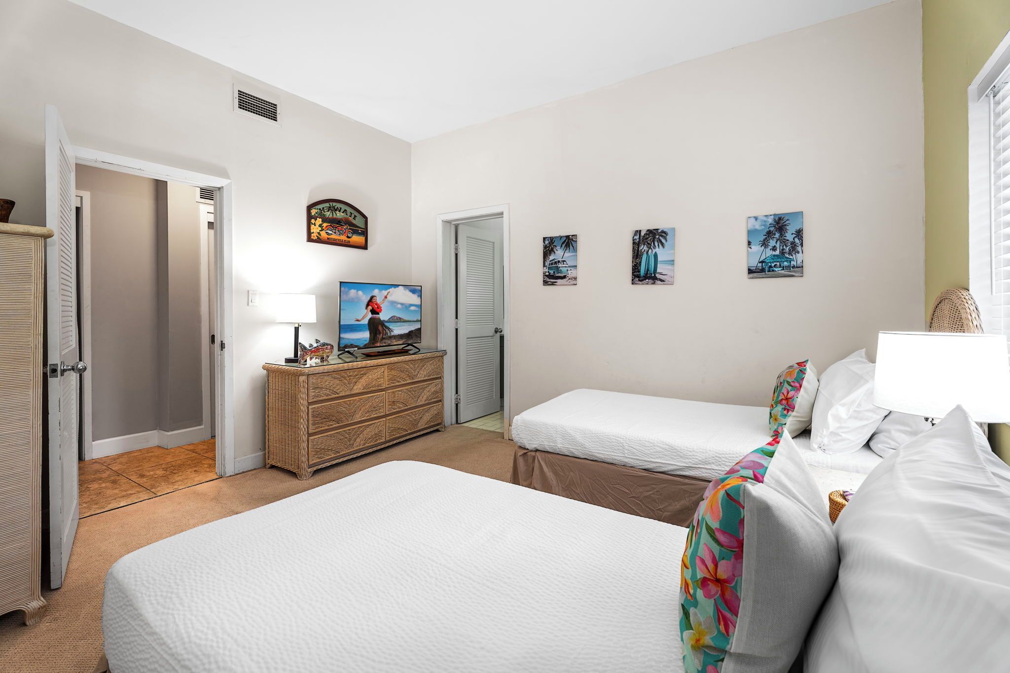 Una habitación de hotel con dos camas, un aparador, un televisor y decoración en la pared.